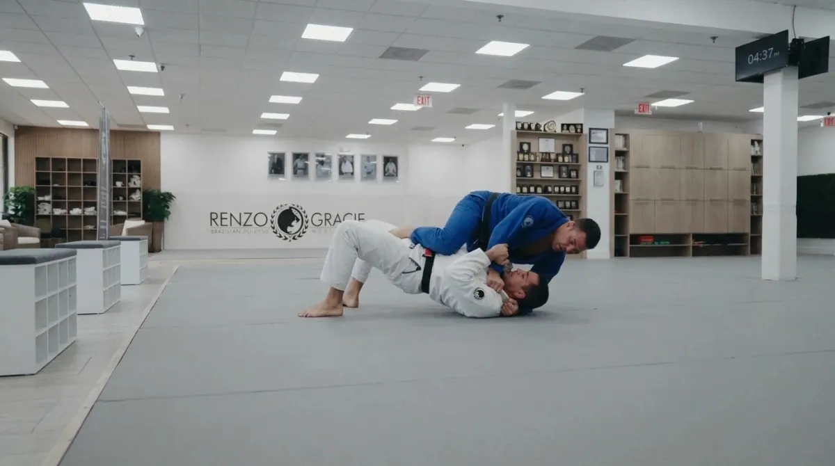 A bottom student trapping a partner's wrist while a foot hooks outside the same leg during the bridge