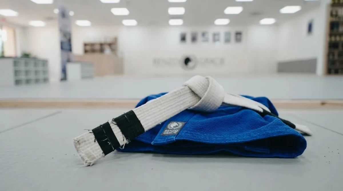 A close-up of a child's white belt with two tape stripes at the end