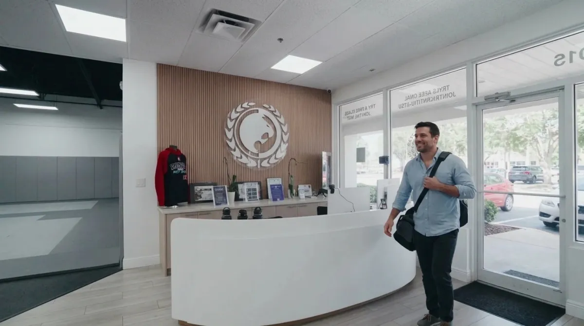 A professional with a gym bag walks into the Renzo Gracie West Boca lobby after work.