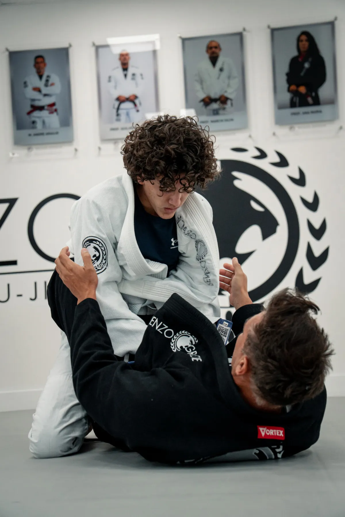 Dos alumnos adolescentes practicando una técnica frente a las fotos de la pared de la academia