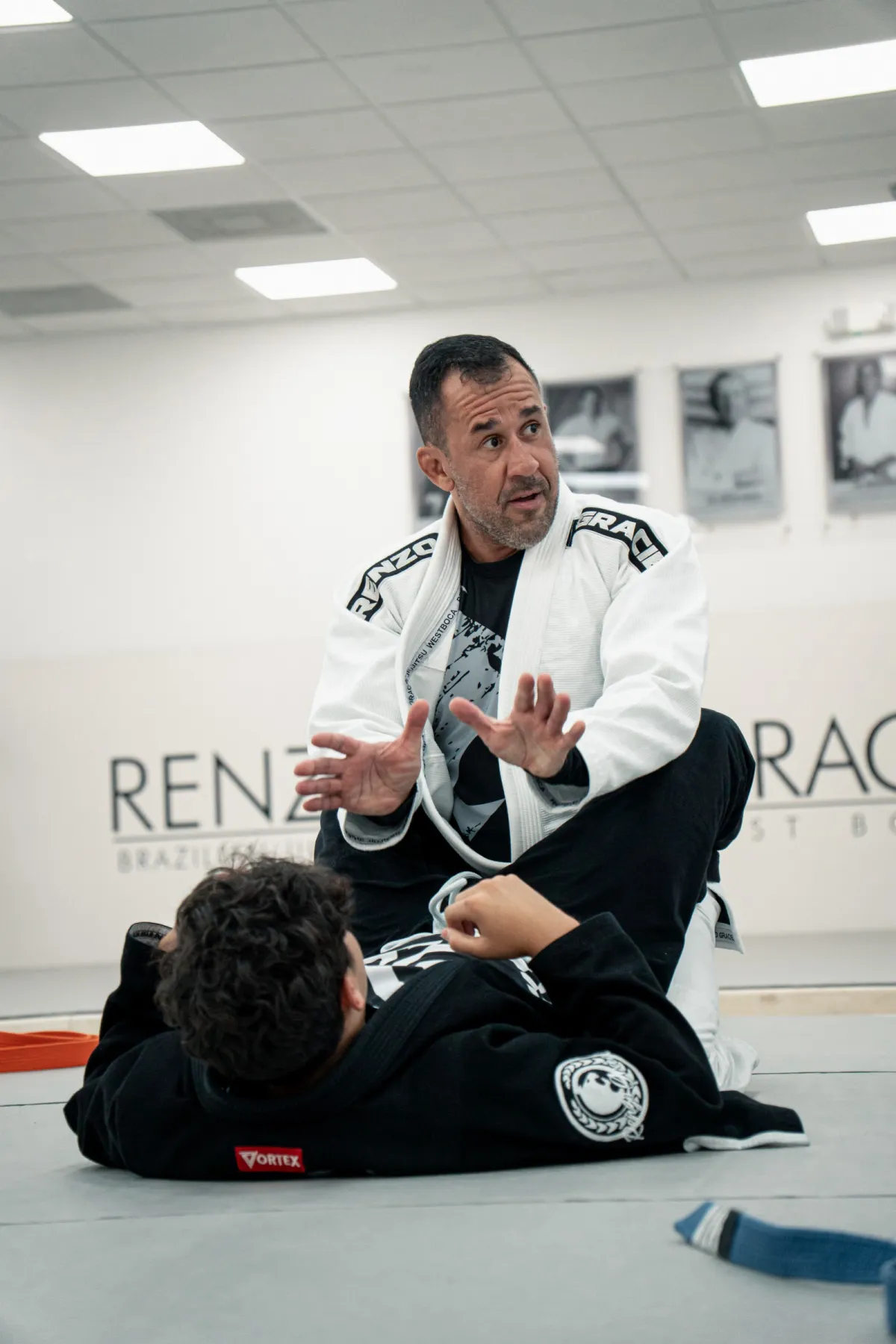 Instructor explicando una técnica a un alumno acostado en el tatami