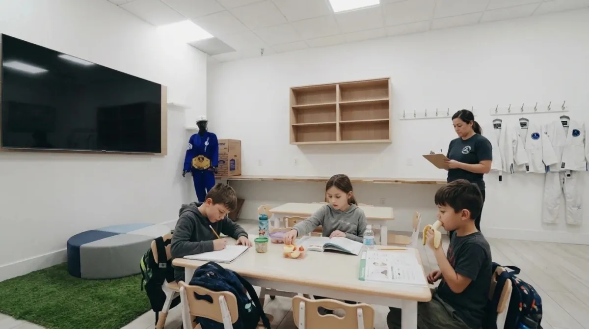 Children doing homework at a table in the academy lobby before class