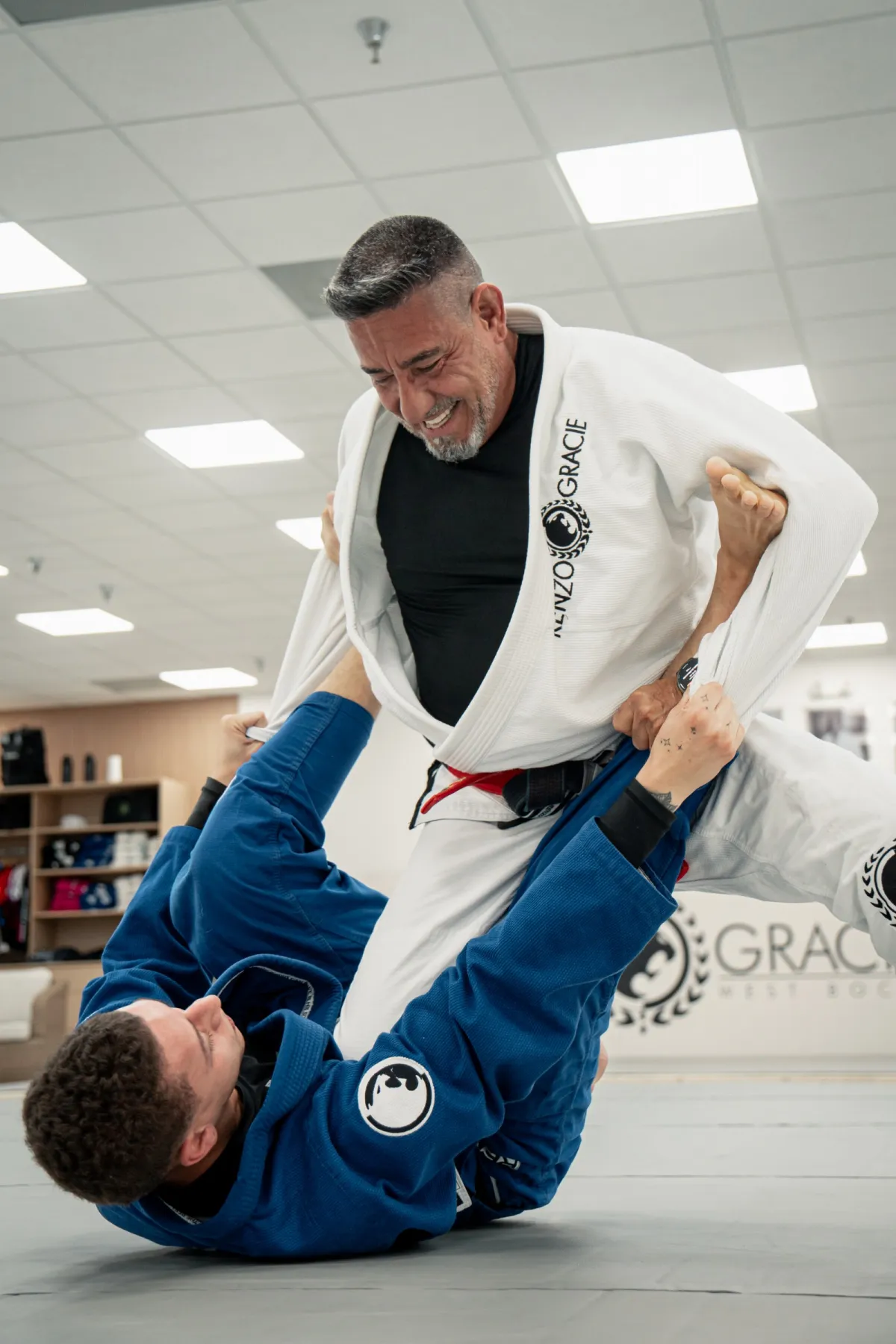Instructor sonriendo mientras entrena con un alumno en el tatami