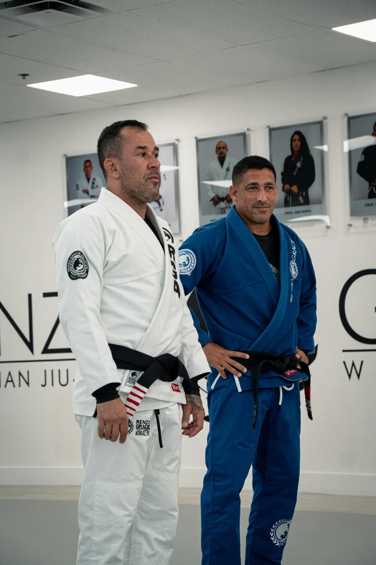 Dos instructores, uno de blanco y otro de azul, de pie juntos en el tatami