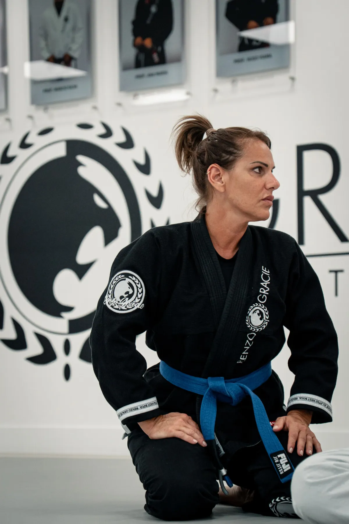 Mujer con kimono negro y cinturón azul arrodillada en el tatami